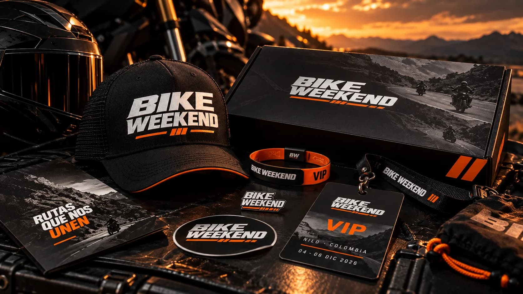Kit de bienvenida Bike Weekend: caja, gorra, manilla VIP, pin, acreditación VIP con lanyard y más piezas sobre una moto al atardecer